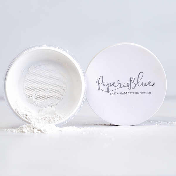 A jar of PiperBlue earth-made setting powder is open with powder visible inside. The product is labeled as 'PiperBlue' and 'Earth-Made Setting Powder'.