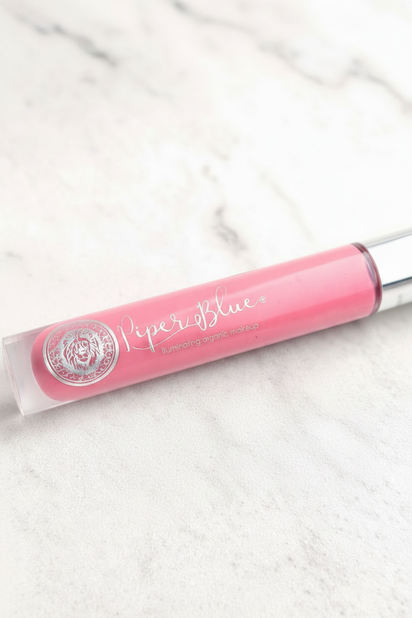 Pink lip gloss with applicator on a white marble surface